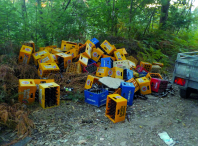 Imaxe de caixóns de cervexas e auga tirados na pista forestal que vai cara Pegariños